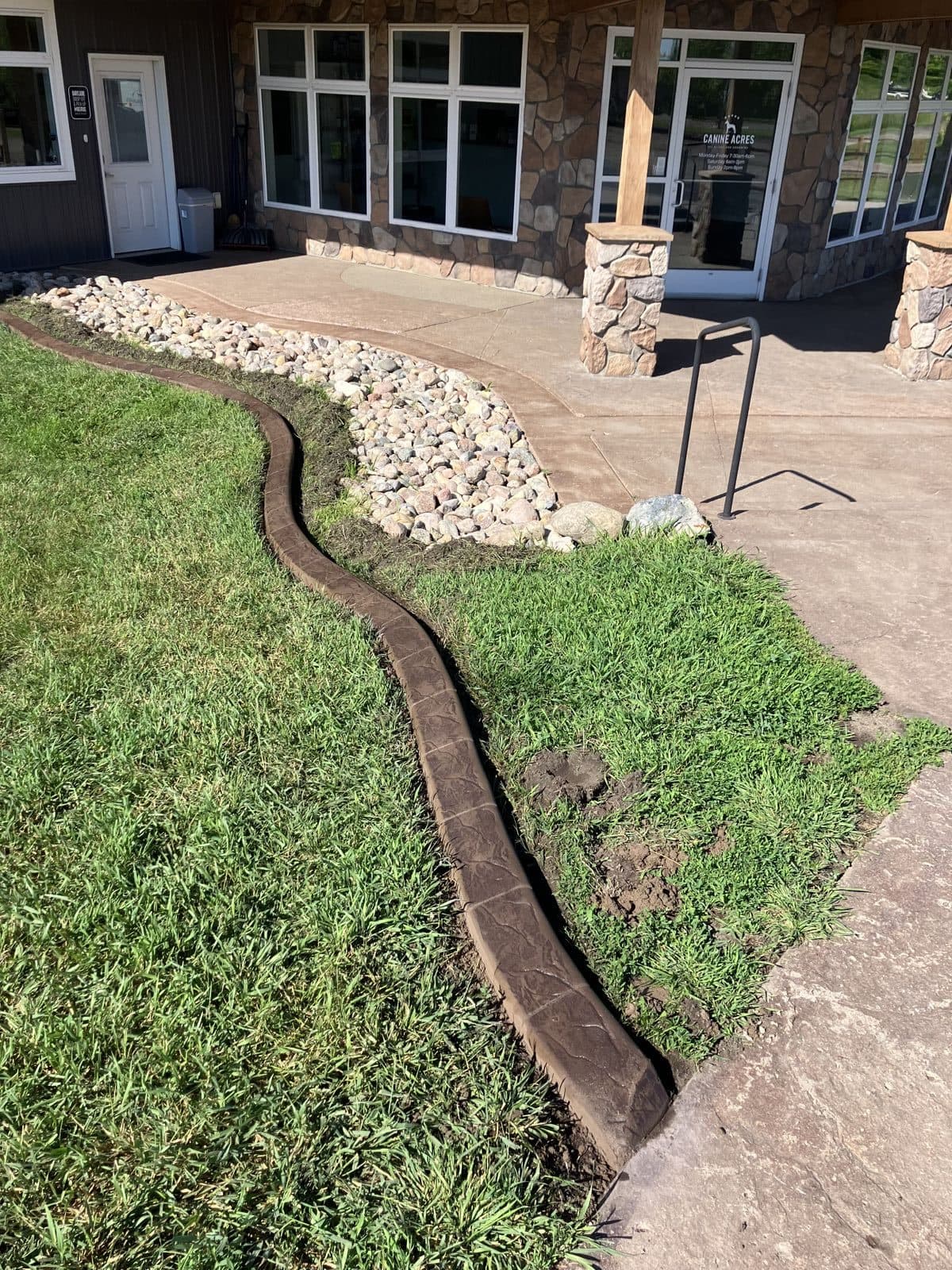 Walnut stamped curbing around a rock landscape bed at Canine Acres